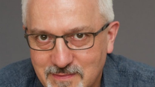 Author Alan Hollinghurst looking slightly amused, with a grey background