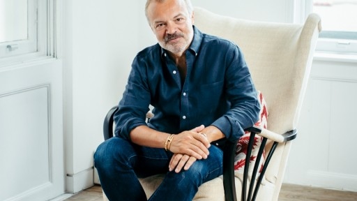 Author Graham Norton smiling and looking relaxed in a comfy armchair