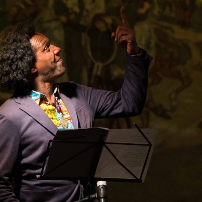 Lemn Sissay performing at Town Hall pointing at ceiling